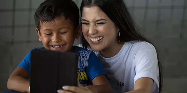 formadora do Aula Digital Profuturo ensina criança a utilizar o tablet do projeto