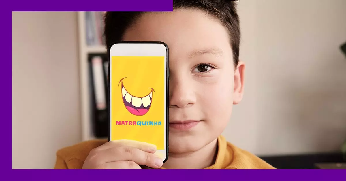 imagem mostra uma criança com um celular na mão, onde se vê o nome do aplicativo Matraquinha
