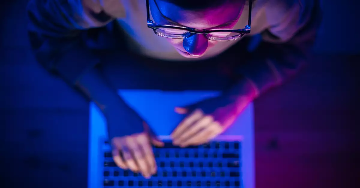 imagem de um jovem, de óculos de grau, digitando em um computador