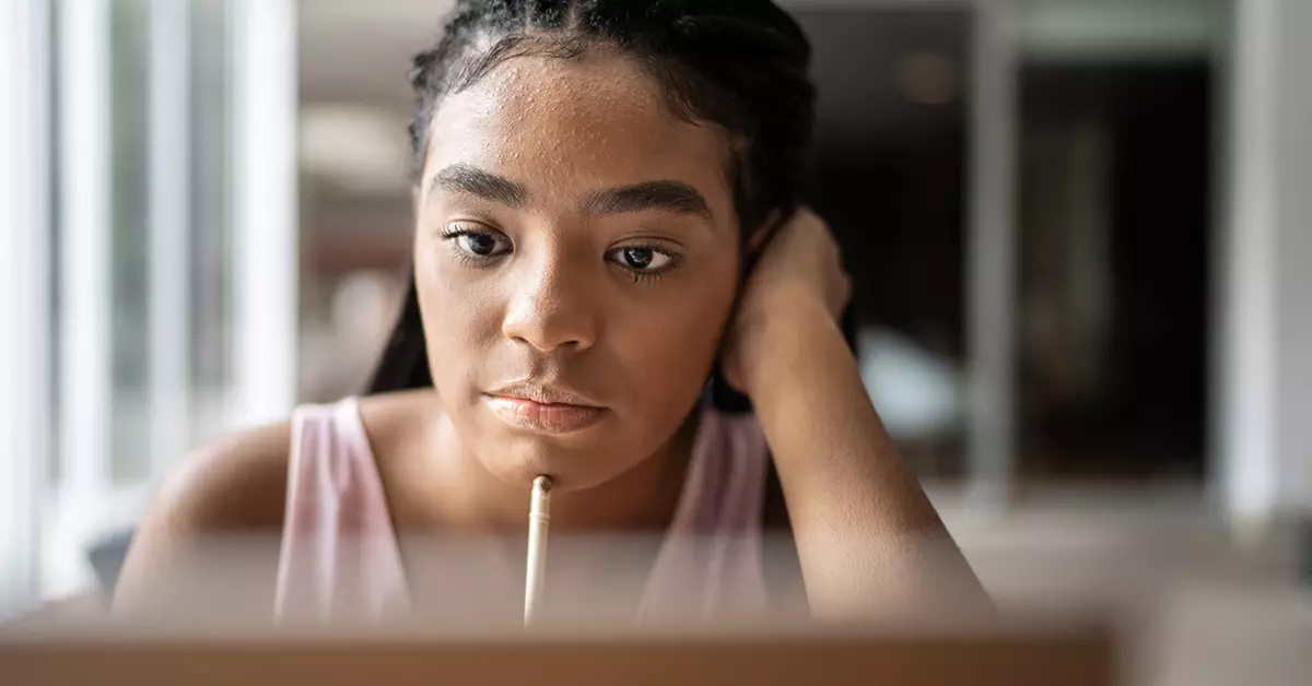 Jovem olha fixamente para tela de computador enquanto apoia lápis no rosto para ilustrar pauta sobre futuro do trabalho. Pesquisa da Unicef aponta visão de jovens sobre educação e emprego