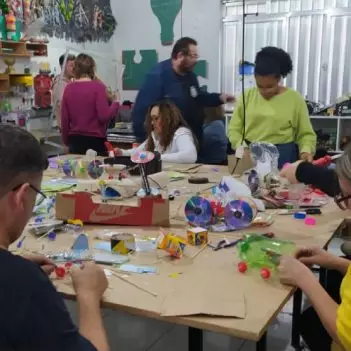 Professores reunidos em torno de uma mesa com sucatas diversas para a construção de protótipos eletrônicos em formação docente em robótica educacional