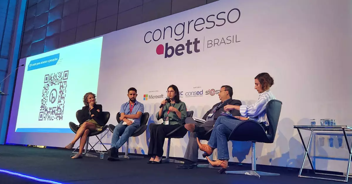 Imagem mostra o palco da Bett Brasil, onde estão sentados em uma palestra os representantes das instituições responsável pela pesquisa lançada durante o evento